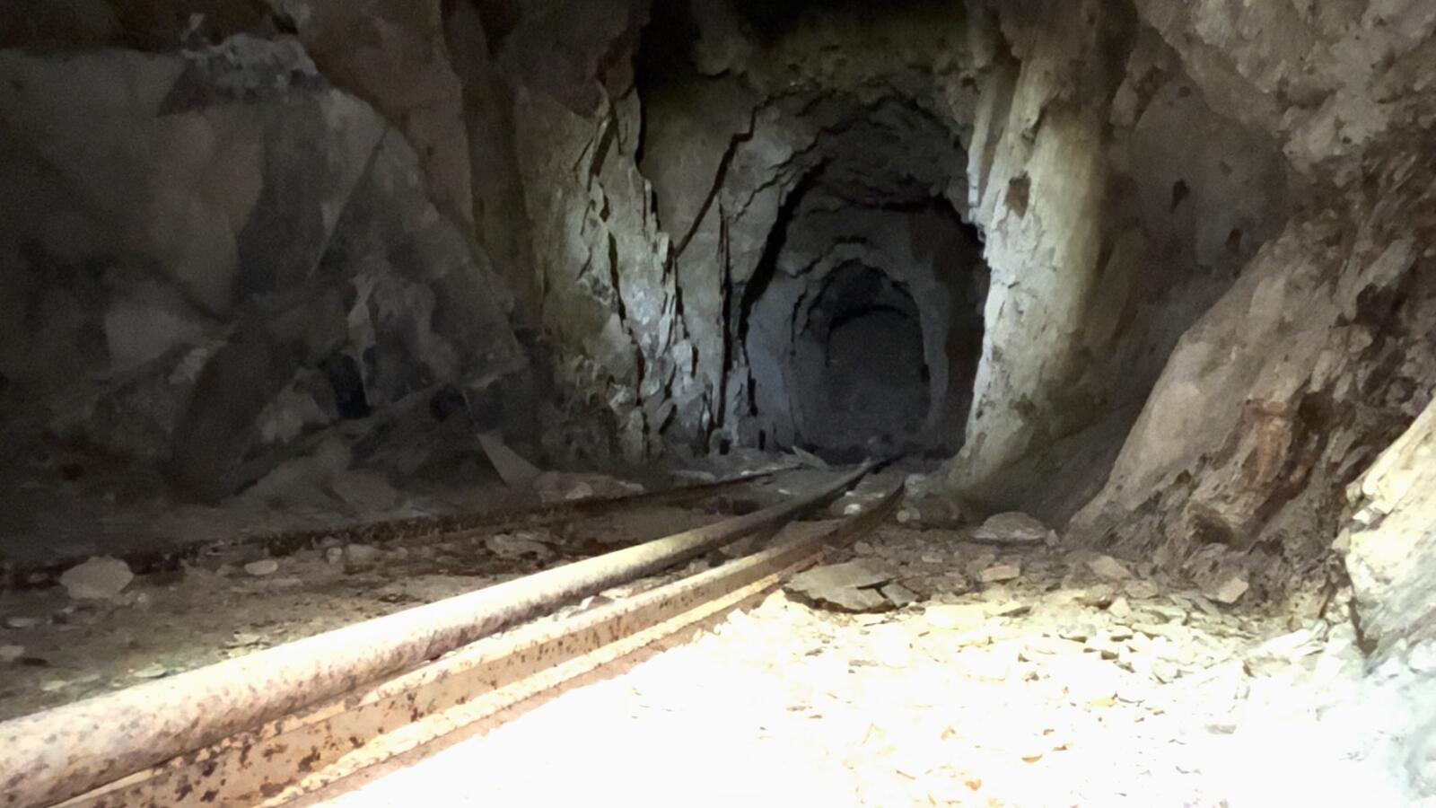 The main drift of the Red Wing Mine looking back along the iron rails laid into the floor, slate walls on either side, the back of the working receding into darkness.