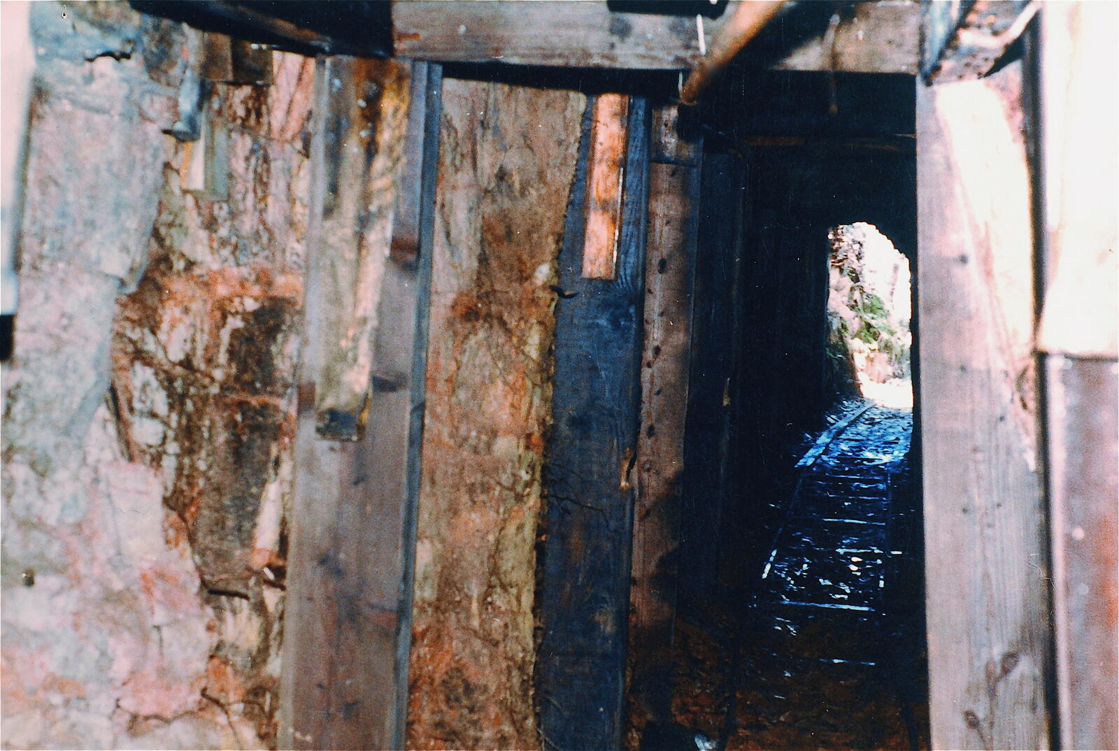 The interior of a worked drift in the Red Wing in the 1980s, heavily timbered with vertical wooden braces along the walls, leading to a daylit opening at the end.