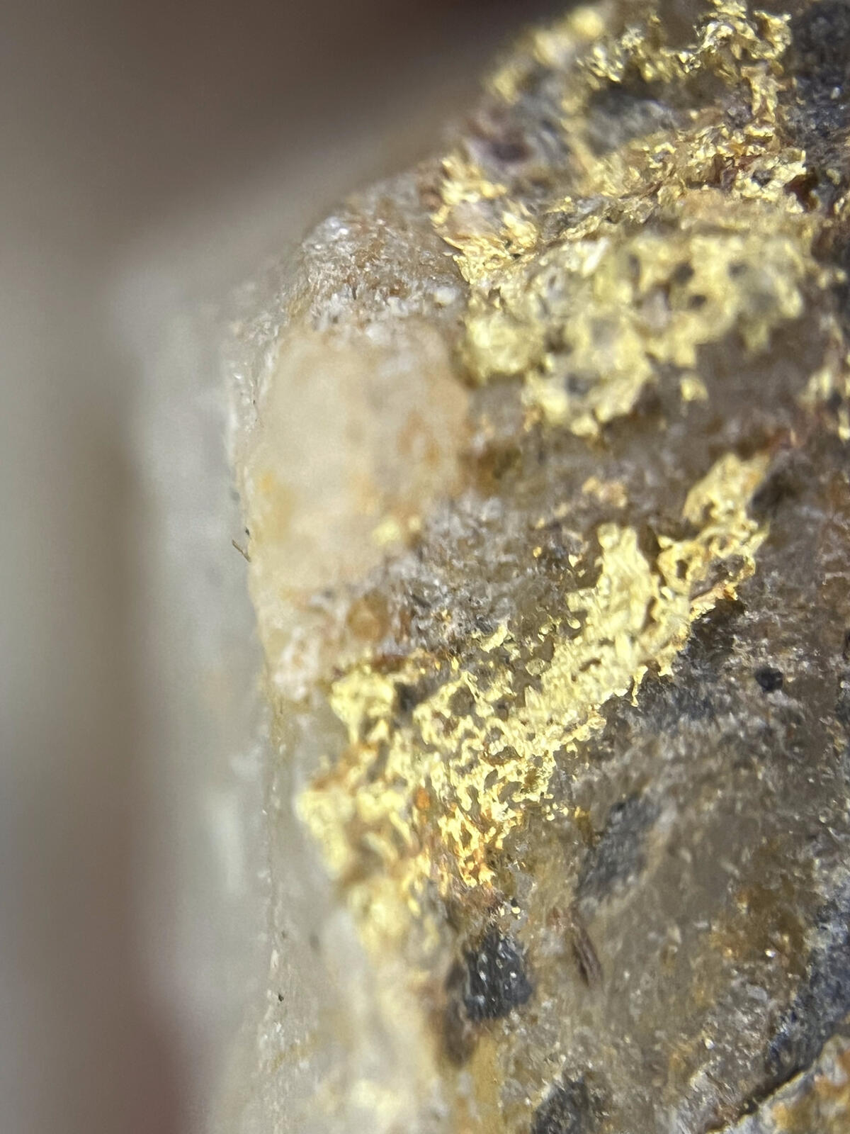 Extreme macro of gold flakes coating the side of a clear quartz crystal.