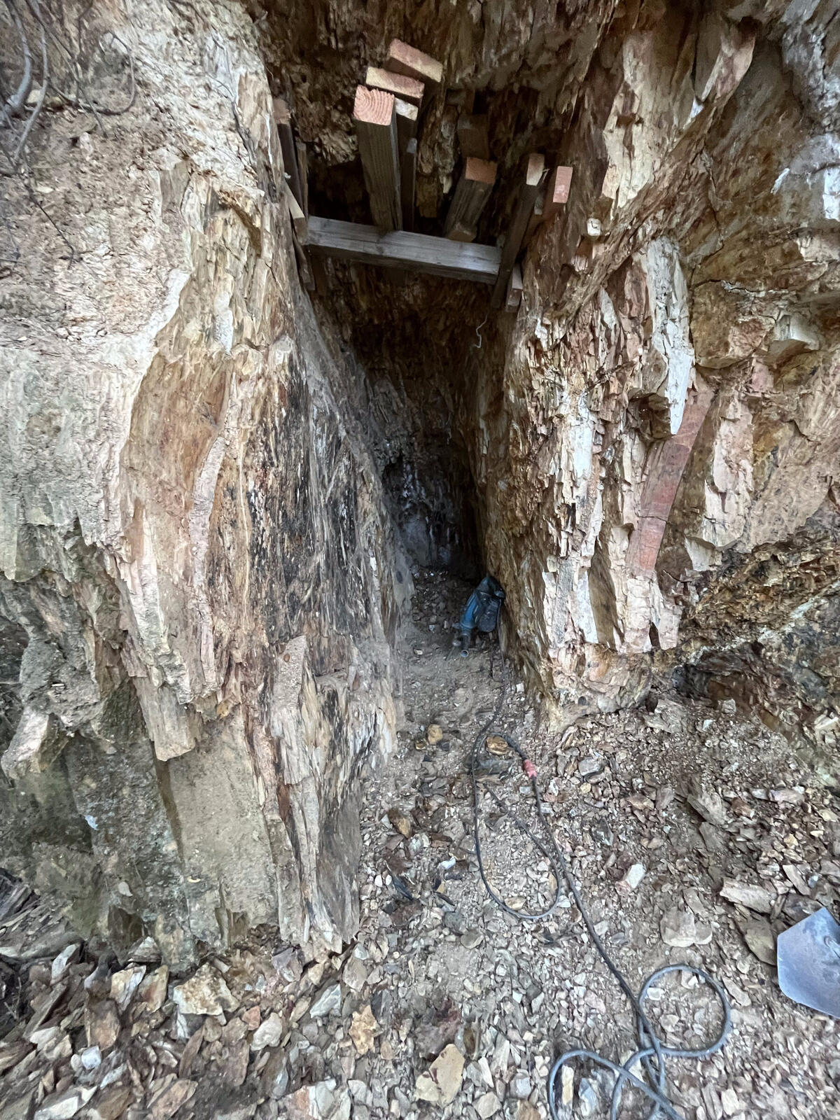 Outside the mine near a collapsed stope at the Red Wing, with wooden boards wedged between rock faces overhead providing ground support.