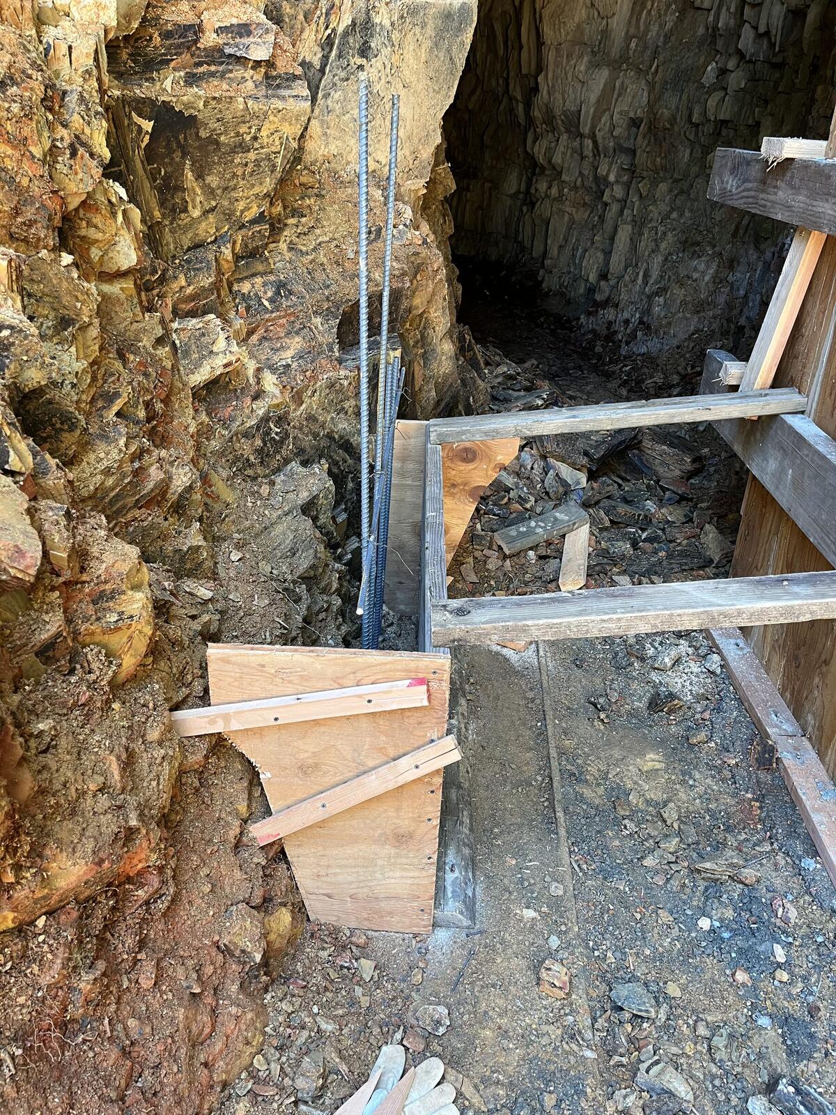 Inside the wooden form for the new concrete portal at the Red Wing, looking out, with plywood walls and plank floor in place and a stack of rebar pieces waiting to be set inside the form before the pour.